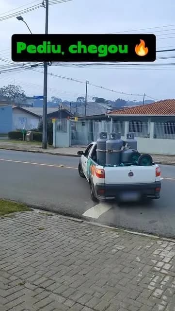 Picape branca de entrega da Lino Gás, com faixa verde e laranja, carregada de botijões P13 e cilindros P45