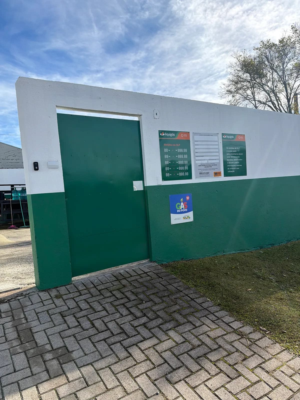 Portão verde da Lino Gás com as placas da Liquigás e a placa Aqui tem Gás do Povo